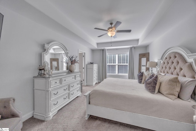 bedroom with ceiling fan, a tray ceiling, and light carpet