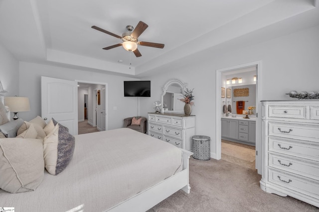 carpeted bedroom featuring ceiling fan, ensuite bathroom, and a raised ceiling