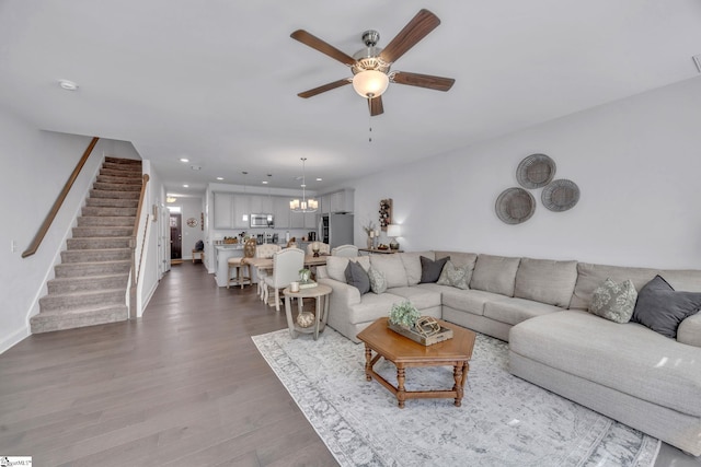 living room with hardwood / wood-style floors and ceiling fan with notable chandelier