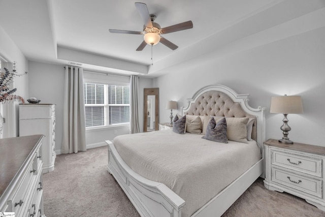 carpeted bedroom with a tray ceiling and ceiling fan