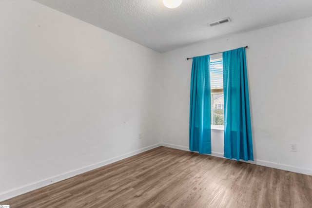 spare room featuring hardwood / wood-style floors and a textured ceiling