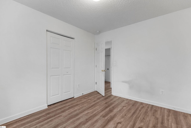 unfurnished bedroom featuring a closet, light wood-type flooring, and a textured ceiling