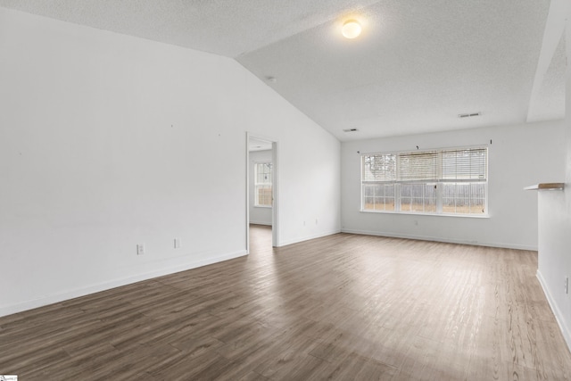 unfurnished living room featuring vaulted ceiling, hardwood / wood-style floors, and a textured ceiling