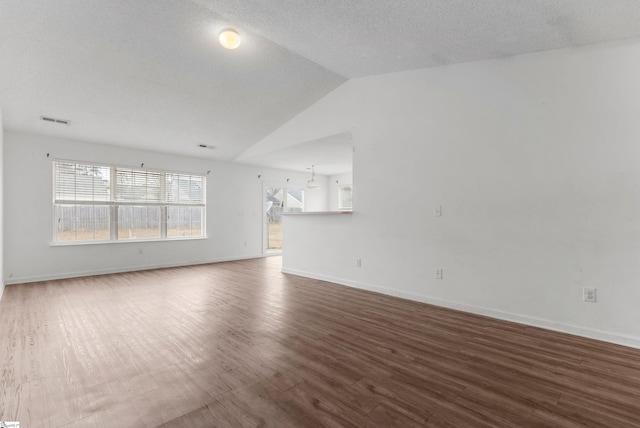 unfurnished living room with a textured ceiling, dark hardwood / wood-style floors, and vaulted ceiling