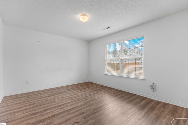 unfurnished room with hardwood / wood-style flooring and a textured ceiling