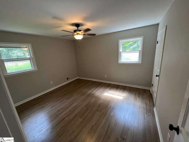 unfurnished room featuring ceiling fan, a wealth of natural light, and dark wood-type flooring