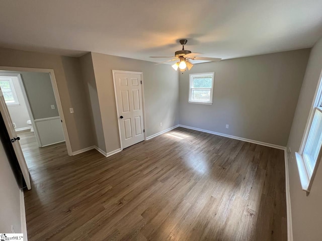 unfurnished room featuring ceiling fan, dark hardwood / wood-style floors, and a healthy amount of sunlight