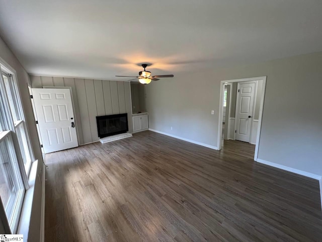 unfurnished living room with ceiling fan, a brick fireplace, and dark hardwood / wood-style floors