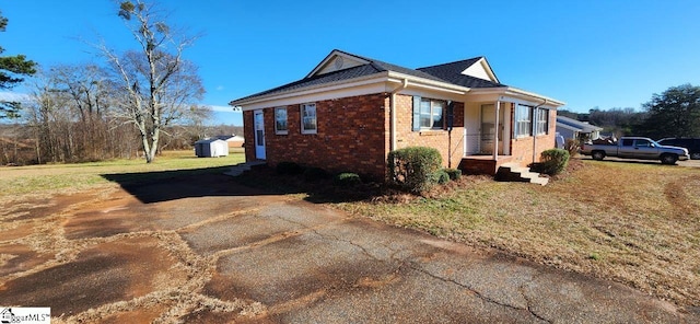 view of side of home with a yard and a storage shed