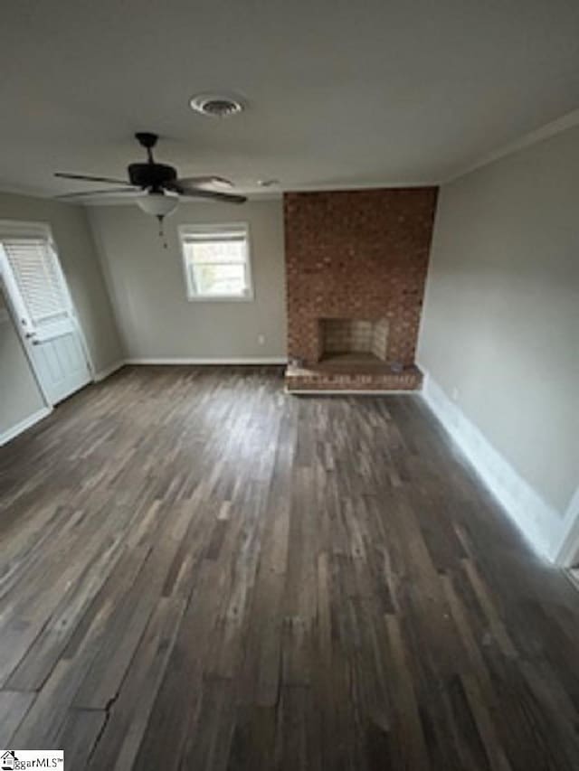 unfurnished living room with ceiling fan, dark hardwood / wood-style floors, ornamental molding, and a fireplace