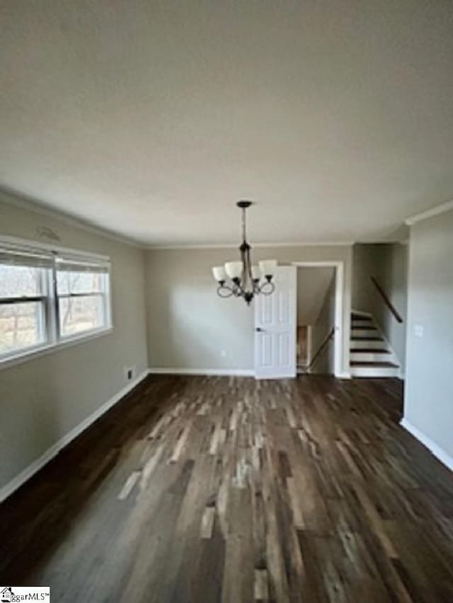 unfurnished dining area featuring dark hardwood / wood-style flooring, ornamental molding, and an inviting chandelier