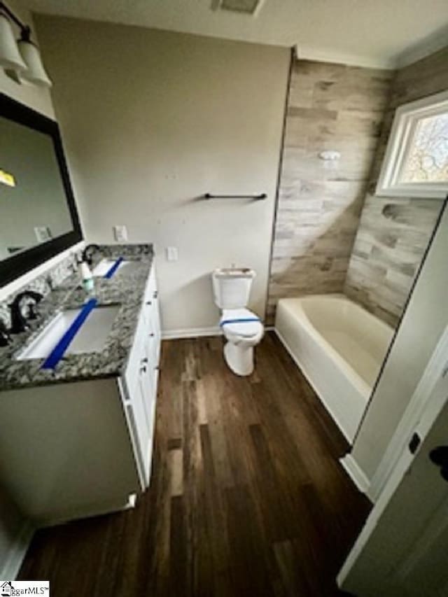 full bathroom with wood-type flooring, washtub / shower combination, toilet, and vanity