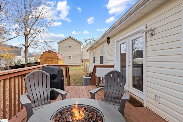 deck featuring a fire pit, central air condition unit, and a storage unit