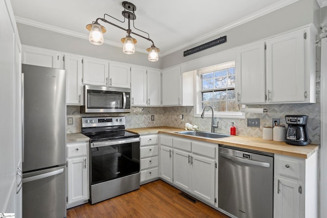 kitchen featuring hanging light fixtures, appliances with stainless steel finishes, sink, white cabinets, and decorative backsplash