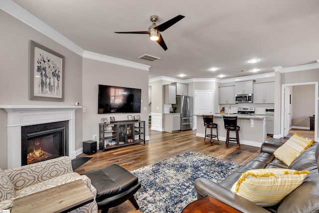 living room with ceiling fan, sink, dark hardwood / wood-style floors, and crown molding