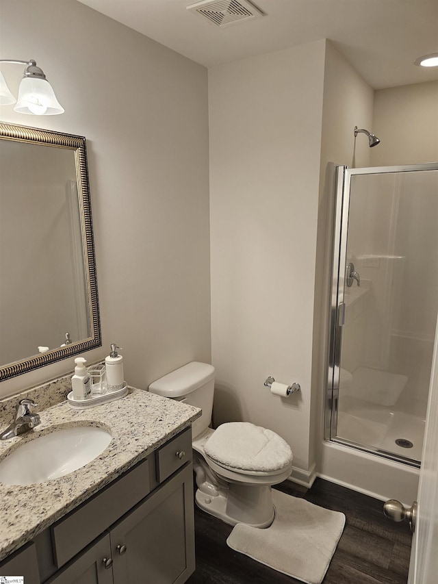 bathroom featuring vanity, a shower with shower door, hardwood / wood-style floors, and toilet