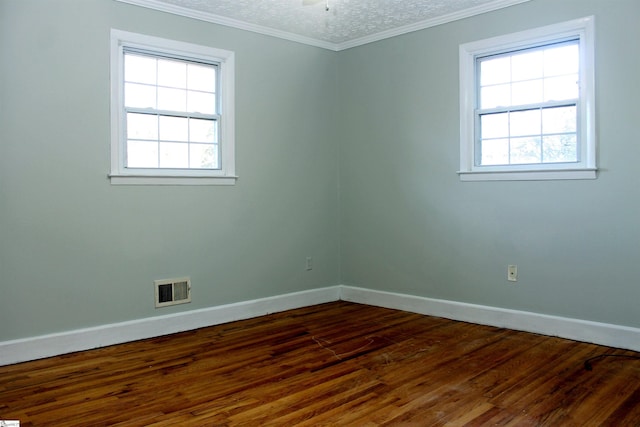 spare room featuring dark wood-type flooring, a textured ceiling, and ornamental molding