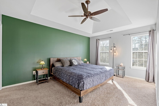 bedroom with ceiling fan, a tray ceiling, and carpet flooring