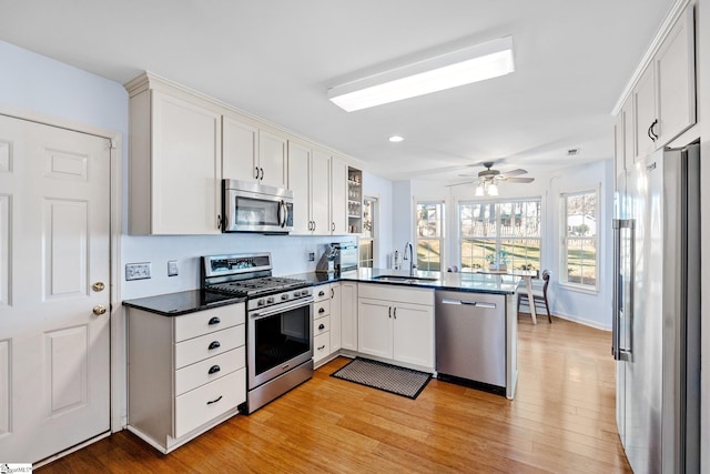 kitchen with light hardwood / wood-style floors, white cabinetry, sink, kitchen peninsula, and stainless steel appliances