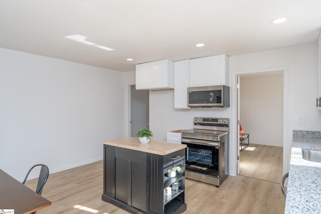 kitchen featuring a center island, white cabinetry, wooden counters, light wood-type flooring, and stainless steel appliances