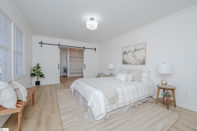 bedroom with ornamental molding, light wood-type flooring, and a barn door