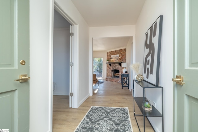 foyer entrance with a brick fireplace and light hardwood / wood-style flooring