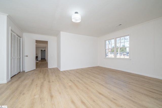 spare room with light wood-type flooring and ornamental molding