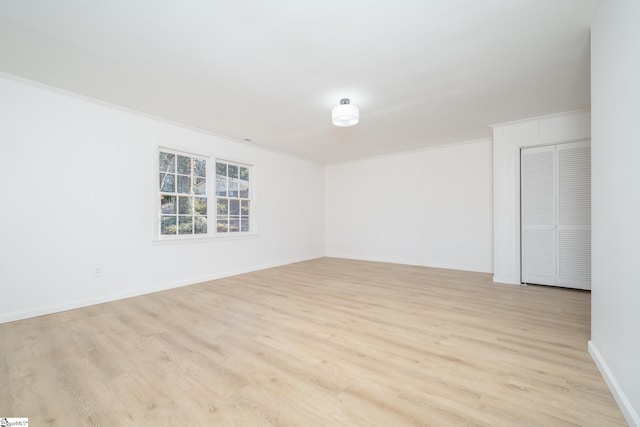 empty room with crown molding and light hardwood / wood-style floors