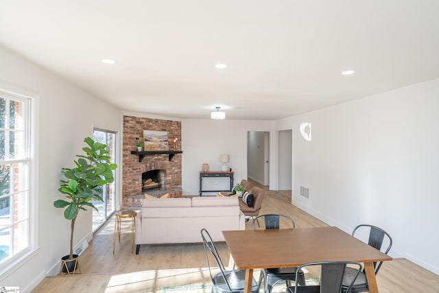 dining room featuring light wood-type flooring and a brick fireplace