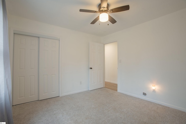 unfurnished bedroom with ceiling fan, a closet, and light carpet