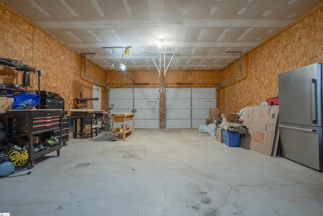 garage featuring stainless steel fridge, a workshop area, and a garage door opener