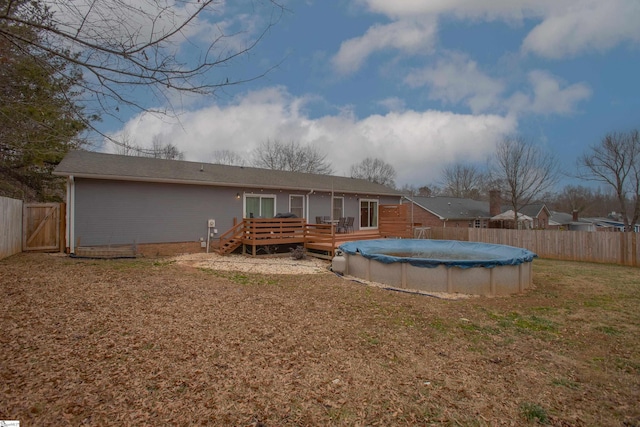 rear view of property featuring a swimming pool side deck and a lawn