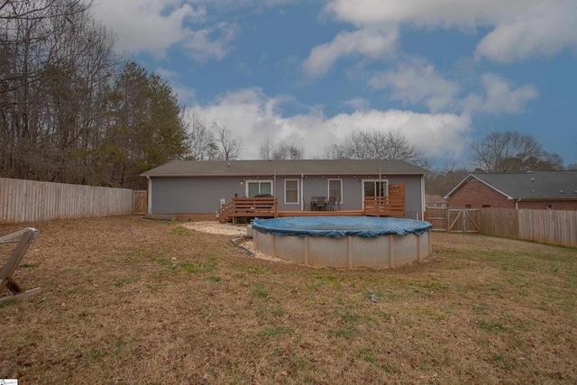 rear view of house featuring a swimming pool side deck and a lawn