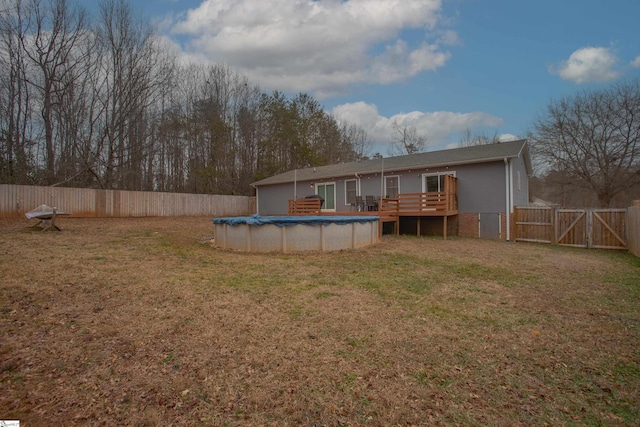 rear view of property featuring a yard and a swimming pool side deck