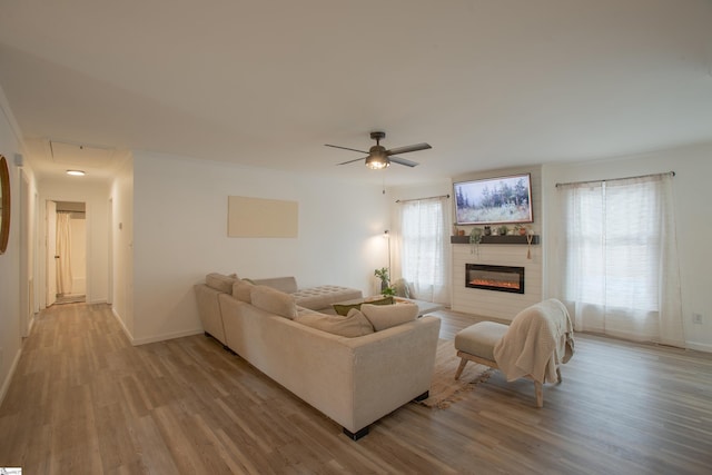 living room with ceiling fan, light hardwood / wood-style floors, and a fireplace