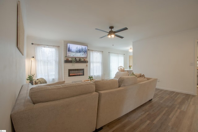 living room with hardwood / wood-style flooring, ceiling fan, and a large fireplace