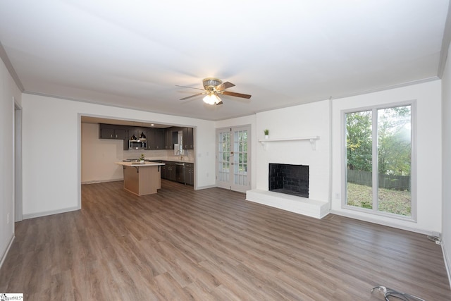 unfurnished living room featuring ceiling fan, wood-type flooring, crown molding, and a fireplace