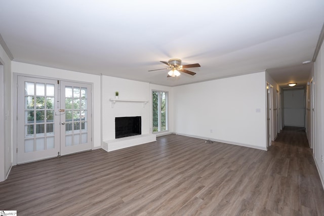 unfurnished living room featuring a fireplace, a healthy amount of sunlight, dark hardwood / wood-style floors, and ornamental molding