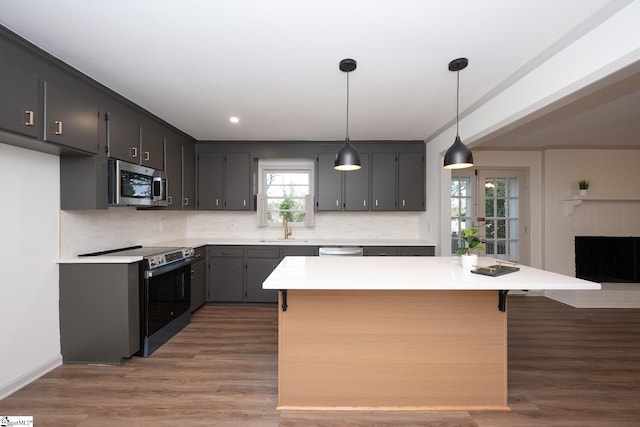 kitchen with decorative light fixtures, dark hardwood / wood-style flooring, stainless steel appliances, decorative backsplash, and plenty of natural light