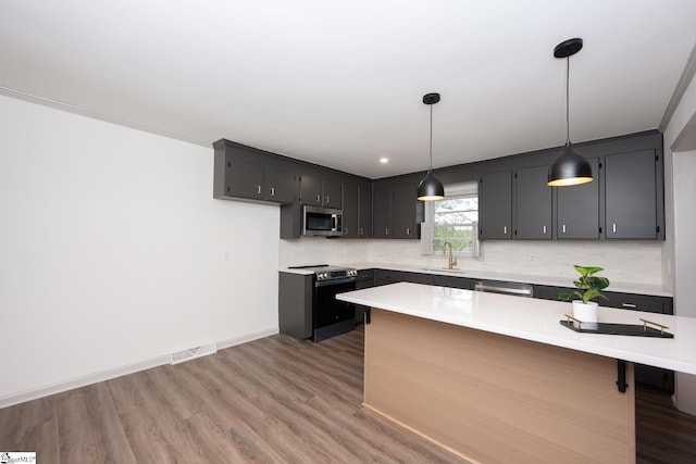 kitchen with hardwood / wood-style floors, tasteful backsplash, sink, decorative light fixtures, and stainless steel appliances