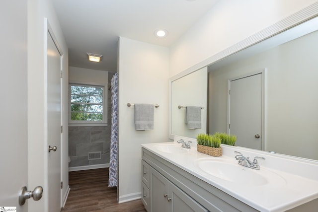 bathroom with hardwood / wood-style floors, walk in shower, and vanity