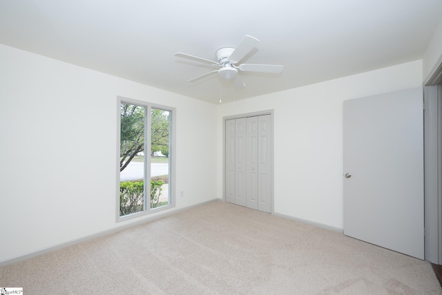 unfurnished bedroom with light carpet, a closet, and ceiling fan