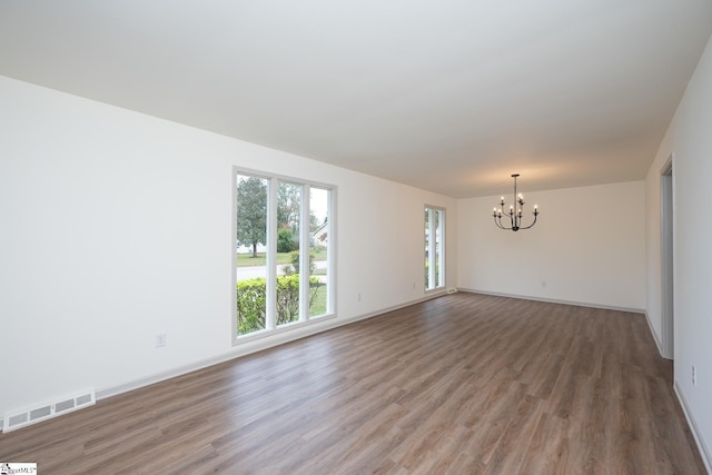 unfurnished room featuring an inviting chandelier and hardwood / wood-style floors