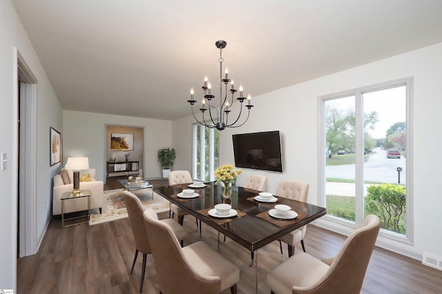 dining room with dark wood-type flooring, plenty of natural light, and a chandelier