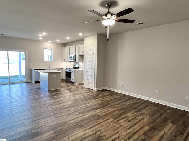 kitchen featuring ceiling fan, white cabinets, a kitchen island, dark hardwood / wood-style flooring, and stainless steel appliances