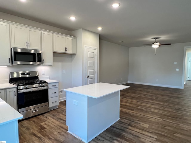 kitchen with a center island, appliances with stainless steel finishes, white cabinetry, dark wood-type flooring, and ceiling fan