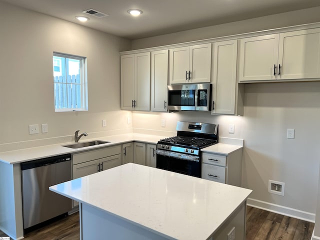 kitchen featuring appliances with stainless steel finishes, dark wood-type flooring, white cabinetry, sink, and light stone counters