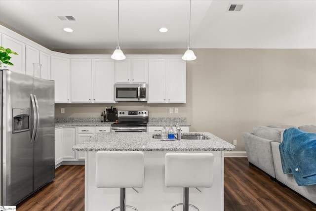 kitchen featuring decorative light fixtures, white cabinets, dark wood-type flooring, and appliances with stainless steel finishes