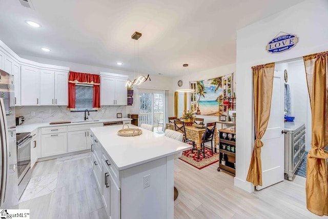 kitchen with decorative light fixtures, white cabinets, tasteful backsplash, stainless steel range with electric stovetop, and a center island