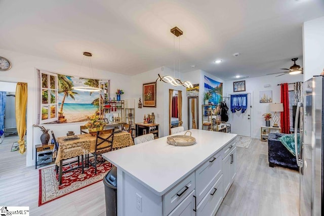 kitchen featuring a center island, light hardwood / wood-style floors, hanging light fixtures, ceiling fan, and stainless steel fridge